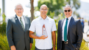 Professor holds award with president and provost