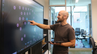 Professor points to large screen in lab