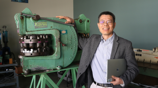 Professor stands next to machining tool
