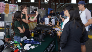 Students display rover at booth as visitors ask questions