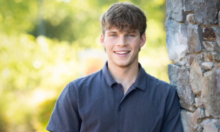Headshot of a Cal Poly student leaning against a tree with foliage in the background