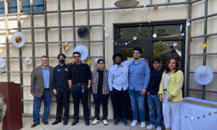 A group of students and mentors posing for a picture in front of celebration decorations