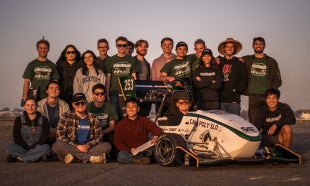 Team members gather around race car after testing