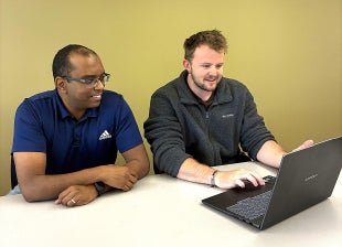 Student and professor work at laptop
