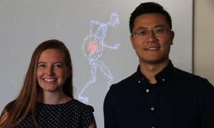 Two professors stand in front of back pain graphic