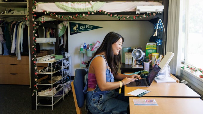 student on laptop in dorm room