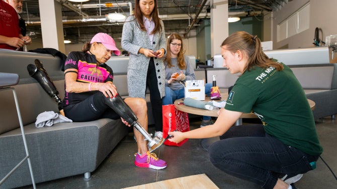 Biomedical engineering majors Oyundari Altansukh and Samantha Campbell with mechanical engineering students Kurtis Barth and Caroline Swanson have amputee Karen Aydelott try out a prototype of a surfing prosthetic they created as part of a team project.