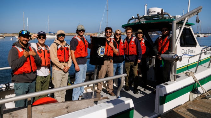 mechanical and electrical engineering students on boat with the Expeditionary Ocean Power Generator (ExOPG)