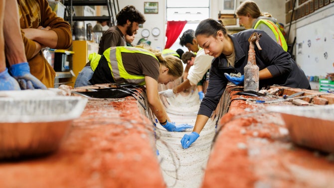 Team members and volunteers apply a lightweight concrete mix to the Cal Poly Concrete Canoe Team’s nearly 20-foot-long canoe mold during the team’s fall practice casting day.