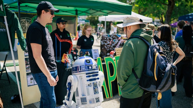 students mingling at open house with r2d2 in front of CAPED booth