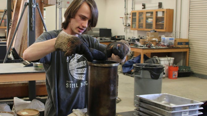 Student works in the Pavement Lab, weighing an asphalt puck