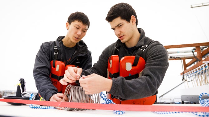 Materials engineering students examine two titanium coils at the Cal Poly Pier as they test the material’s potential for use in an artificial reef.
