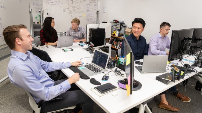 computer engineering students working together at desk with laptops