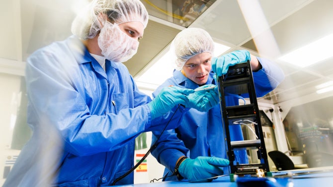 Aerospace students completing a side panel integration on the CubeSat in the clean room.