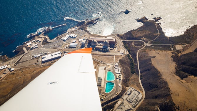Wing view of new Cirrus SR22T aircraft in the sky overlooking ocean and buildings