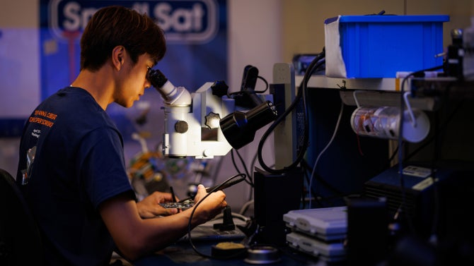 CubeSat team member Berfredd Quezon solders a circuit board in the CubeSat Lab