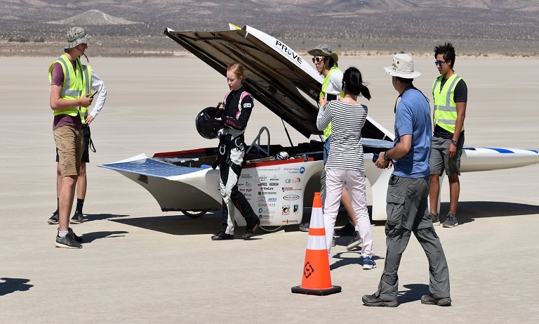 Men and women in front of solar car.