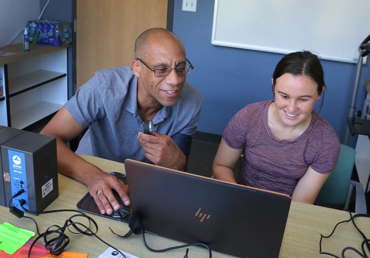Professor Michael Whitt working with student on laptop