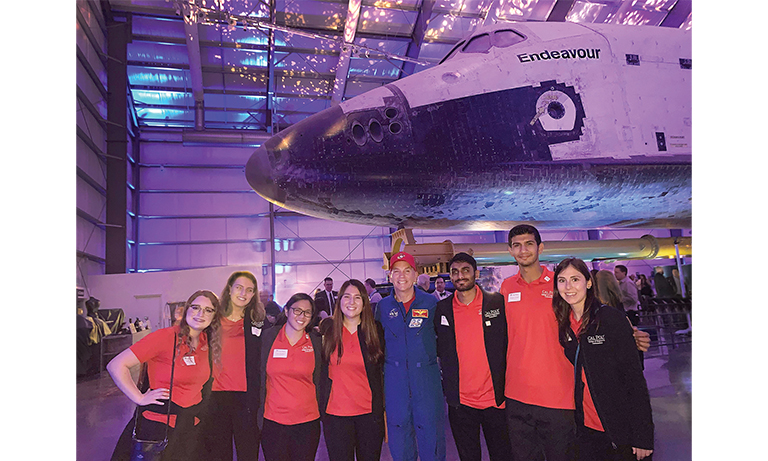 Students and astronaut below space shuttle