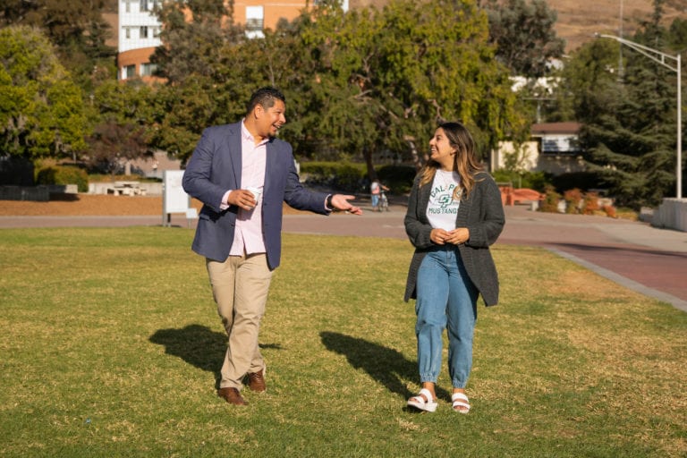 Student and staff member chatting outdoors on campus