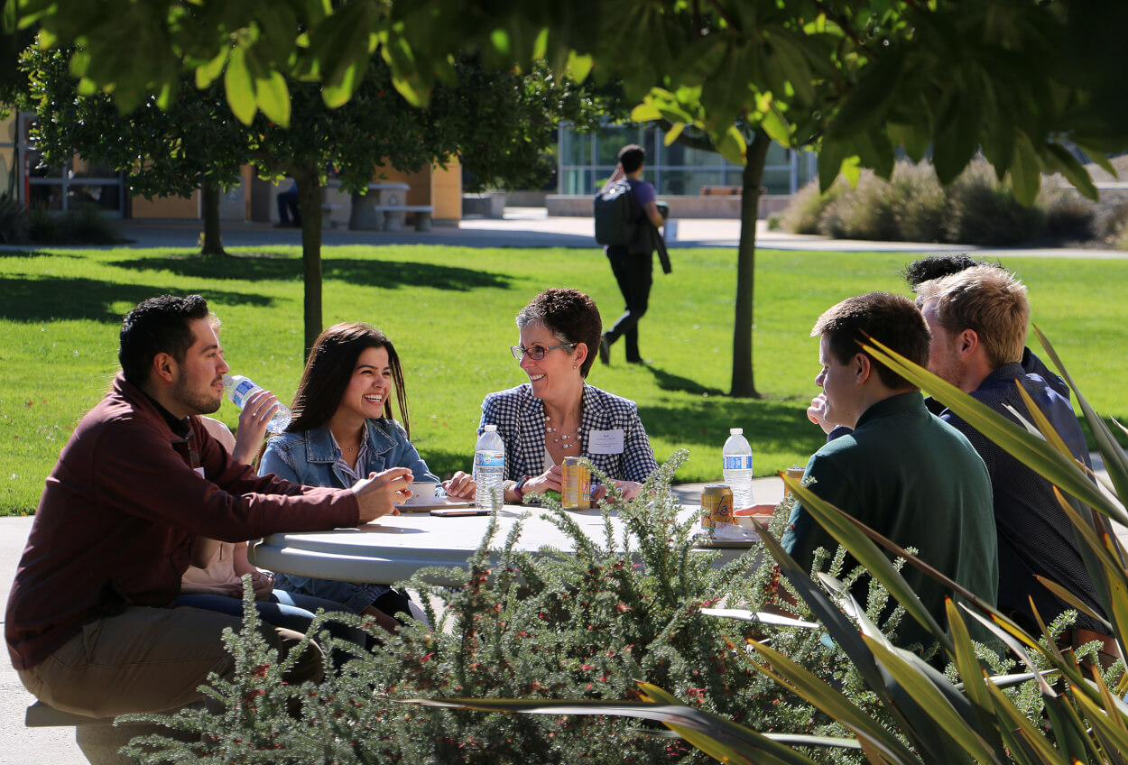 Industry representative sitting and conversing with students outdoors