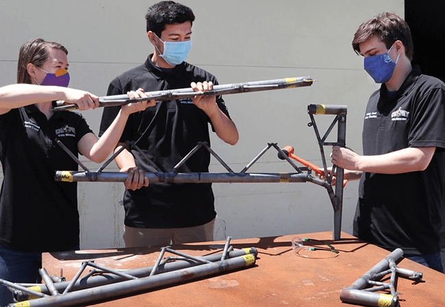 Civil Engineering students Katie Evans, Fabien Leon and Macky Hamilton demonstrate assembly of the Cal Poly Steel Bridge they designed and built for competition