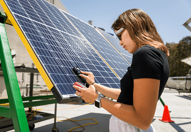Mechanical Engineering student Sophie Getty takes measurements from solar panels outside the solar lab as part of the Summer Undergraduate Research Program (SURP)