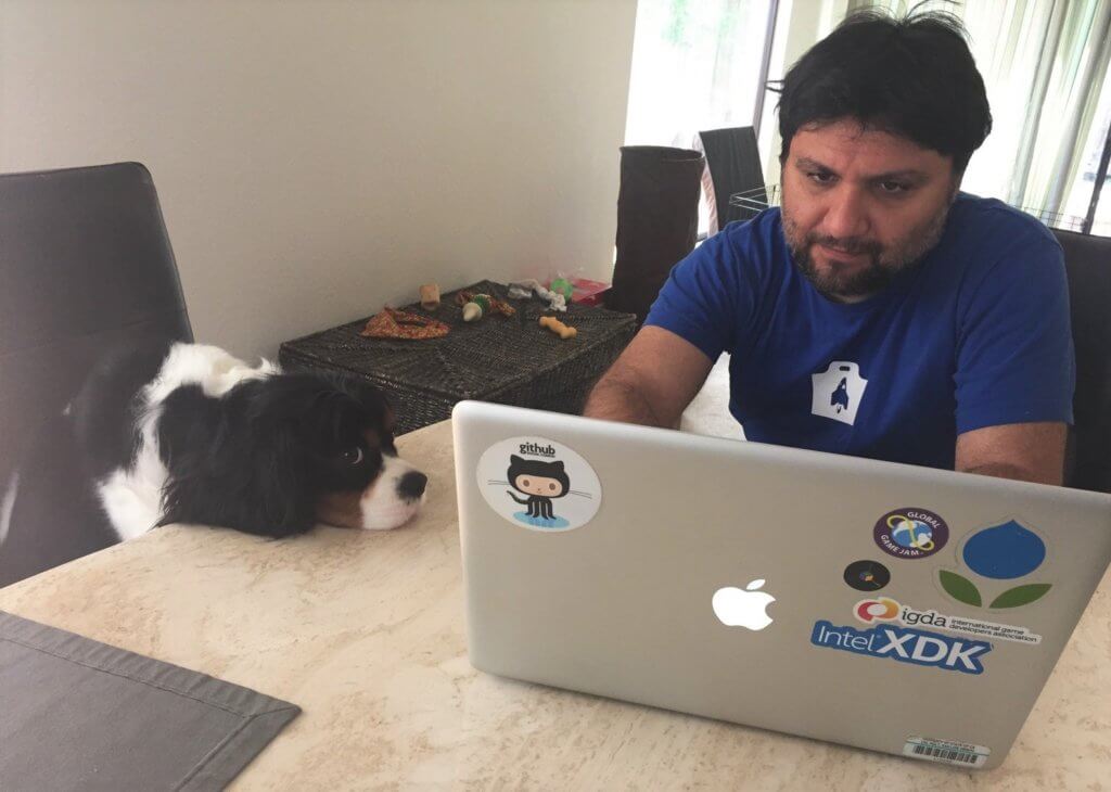 Man working on computer next to dog.