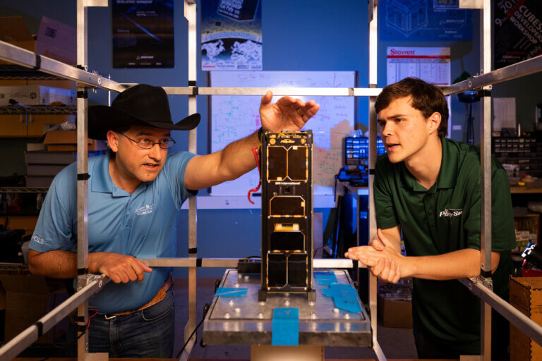 John Bellardo, right, measures a mini satellite in the CubeSat Lab. Cal Poly's CubeSat efforts have been inducted into the Space Technology Hall of Fame.