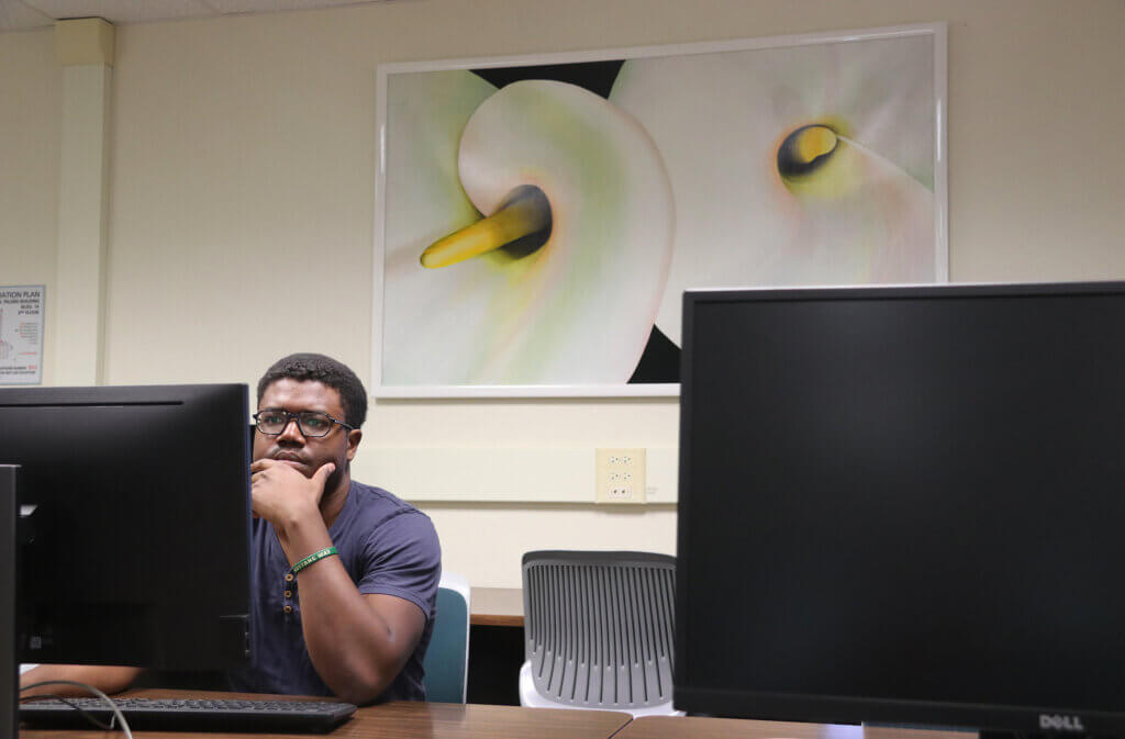 CSSE student Marquis Smith studies in fromt of "Calla Lilies," a painting donated by Annie Armstrong