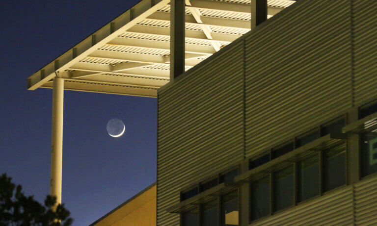 Moon rising by building