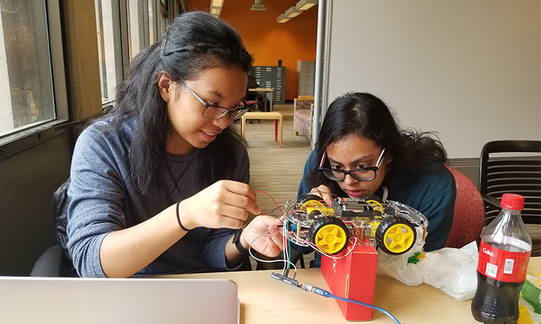 Two women working on robot