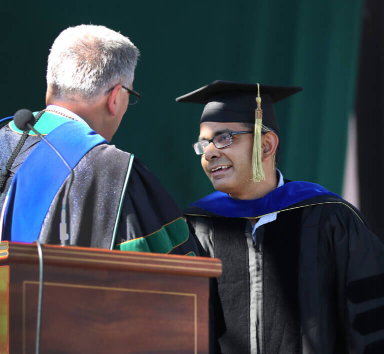 2022 Spring Commencement: Civil and environmental engineering professor Anurag Pande was honored for his teaching on stage by President Jeffrey Armstrong, left, during graduation ceremonies.
