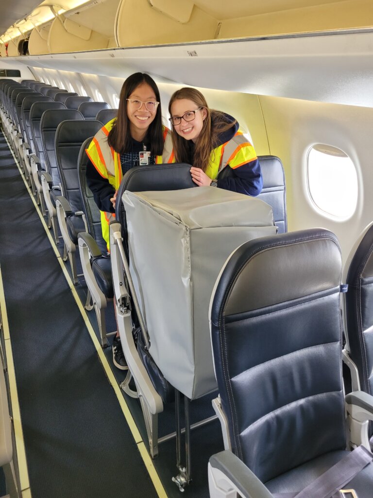 Lauren Chan (left) and Claire Franz testing their anthropomorphic cargo system prototype on a commercial plane 