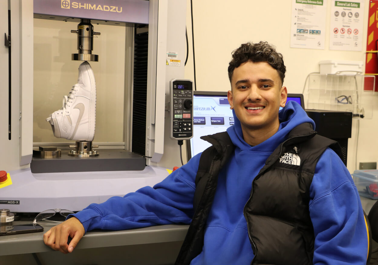 Materials Engineering student Juan Carlos Palominos poses in front of a machine that examines objects.