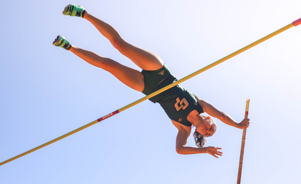 Student successfully jumps over the bar in a pole vault contest