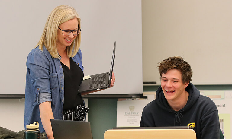 woman holding laptop helping student