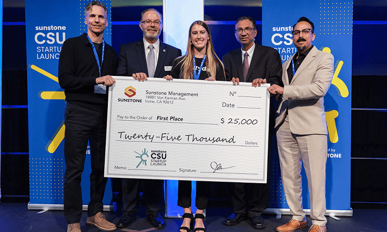 Recent graduate holds check for $25,000 after winning competition