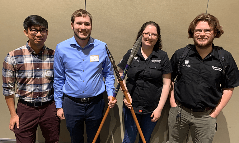 Four students stand with winning African spears
