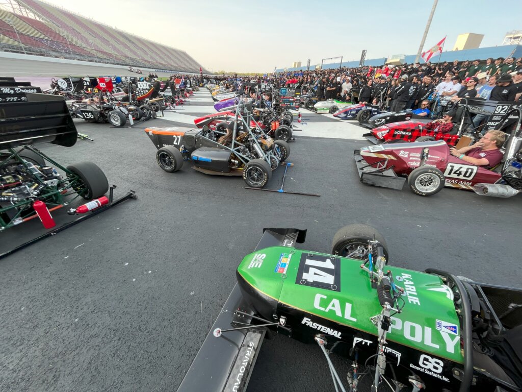 Cal Poly's race car sits next to other competitors' cars at the racetrack