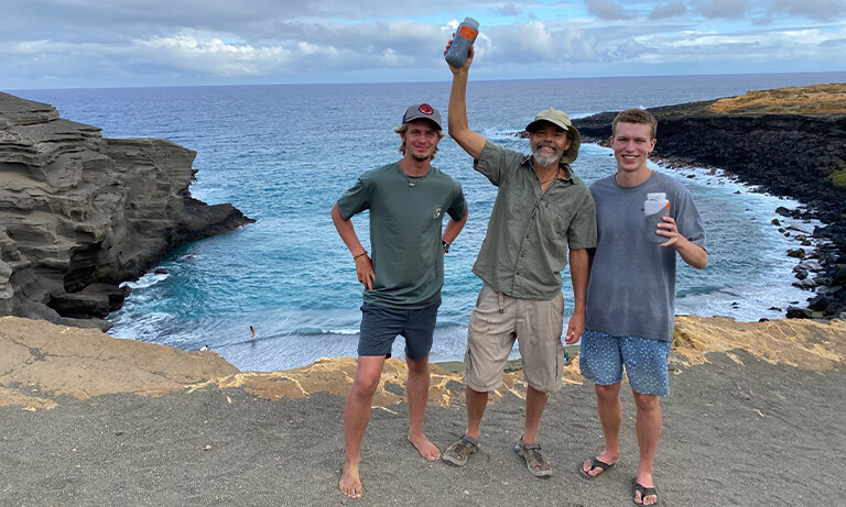 Professor and two students stand on a Hawaii beach where they were researching climate change