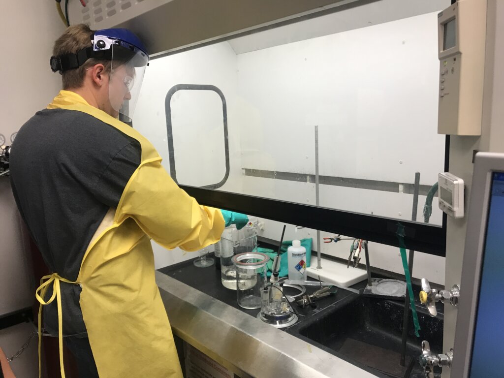 Student fills container with hydrochloric acid while wearing protective gear