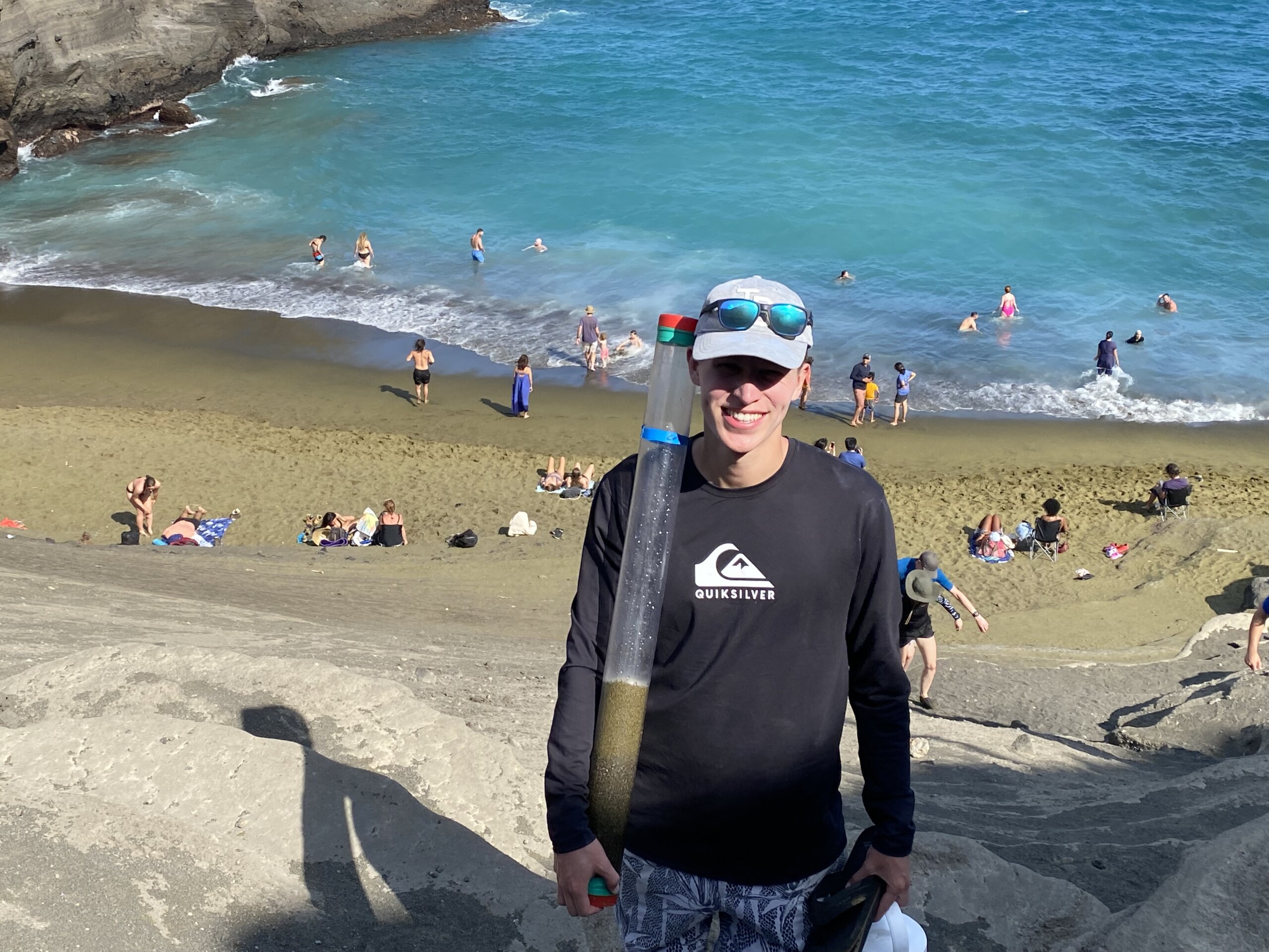Cal Poly student has a sample of green sand during a research trip to Hawaii