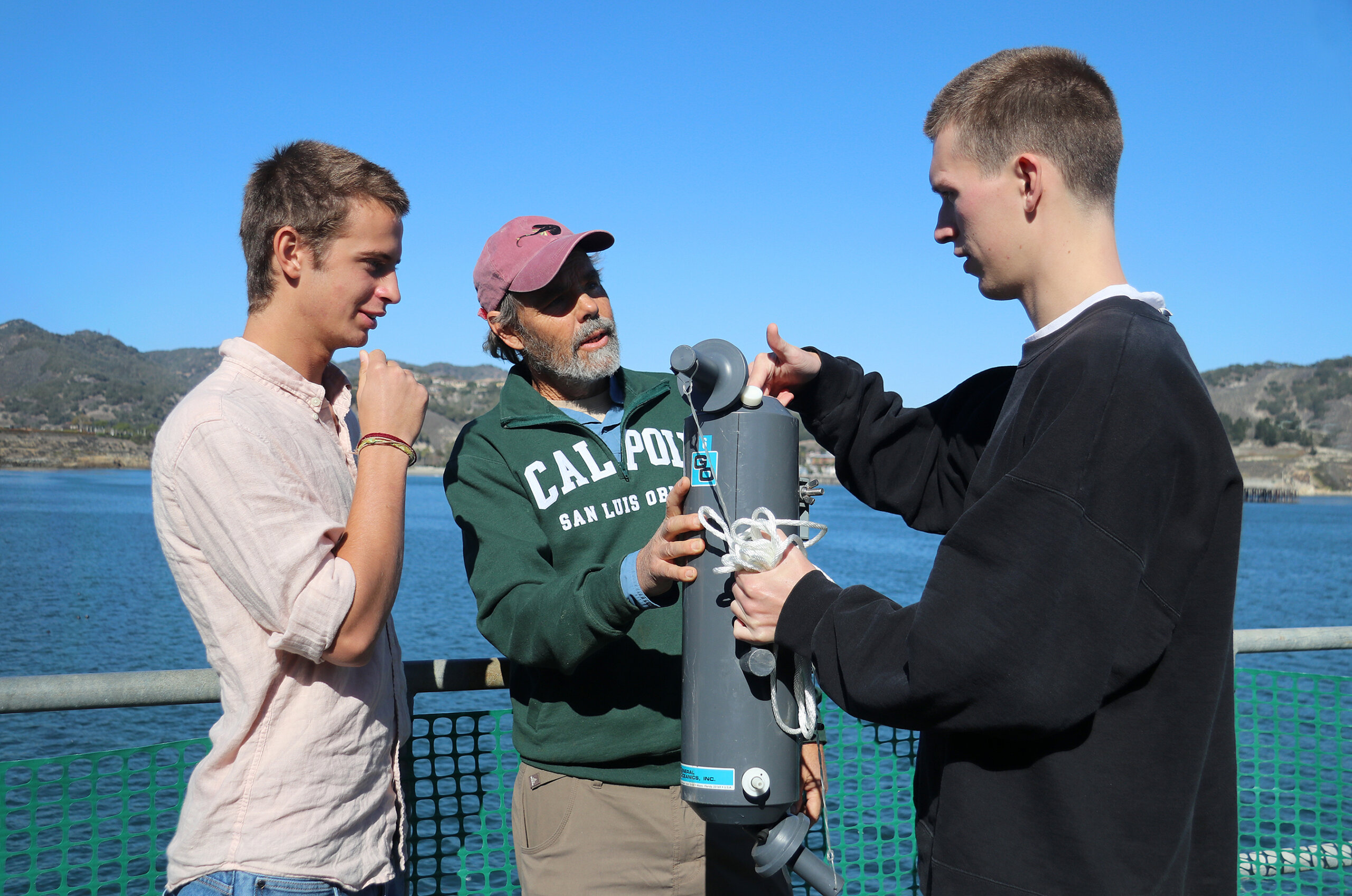 A Cal Poly professor and two students collect ocean water at the Cal Poly Research Pier