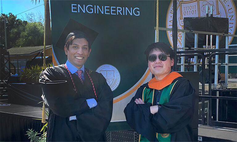 Graduates pose in front of an engineering sign