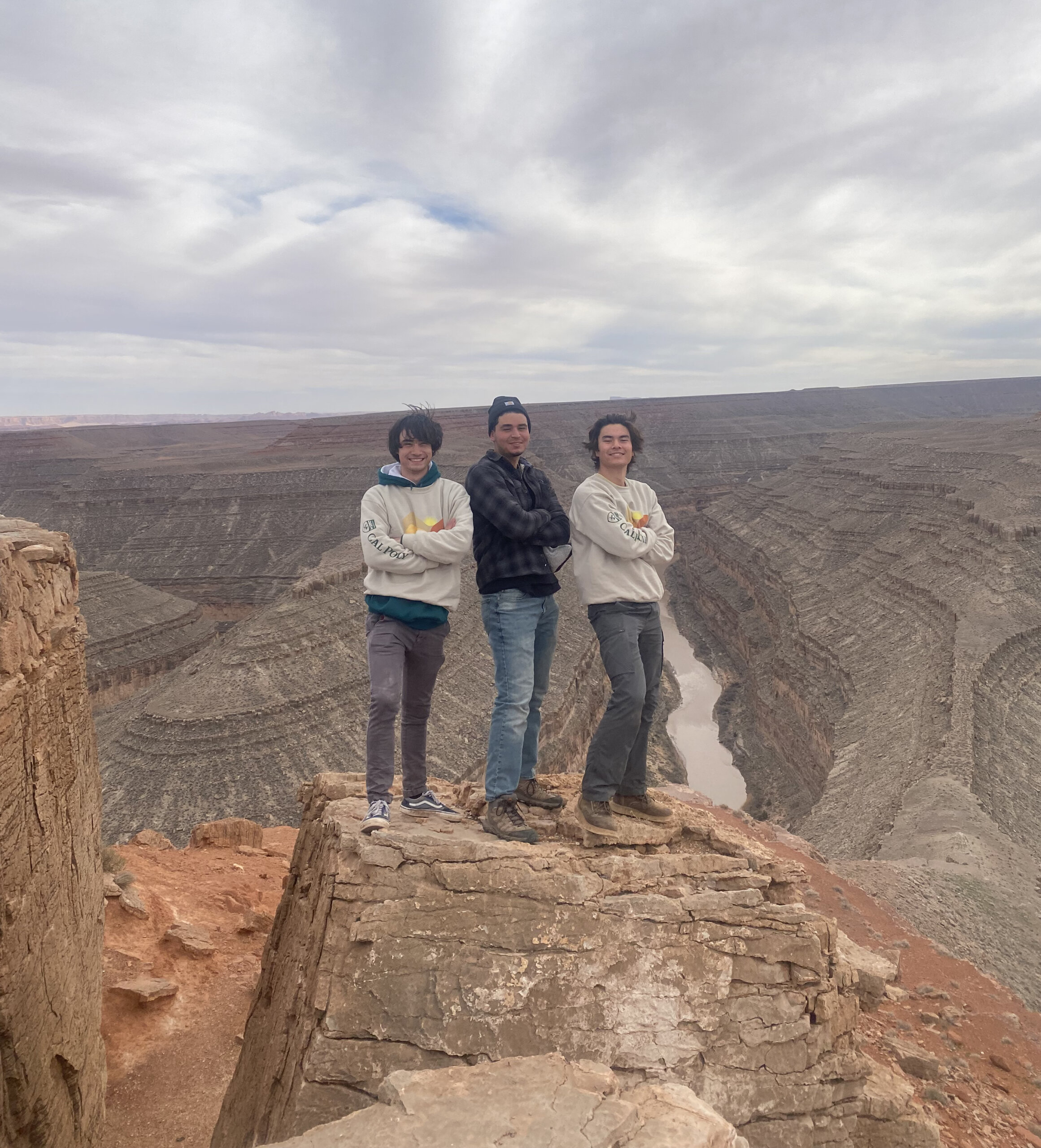 Three students stand atop a cliff in the Navajo Nation