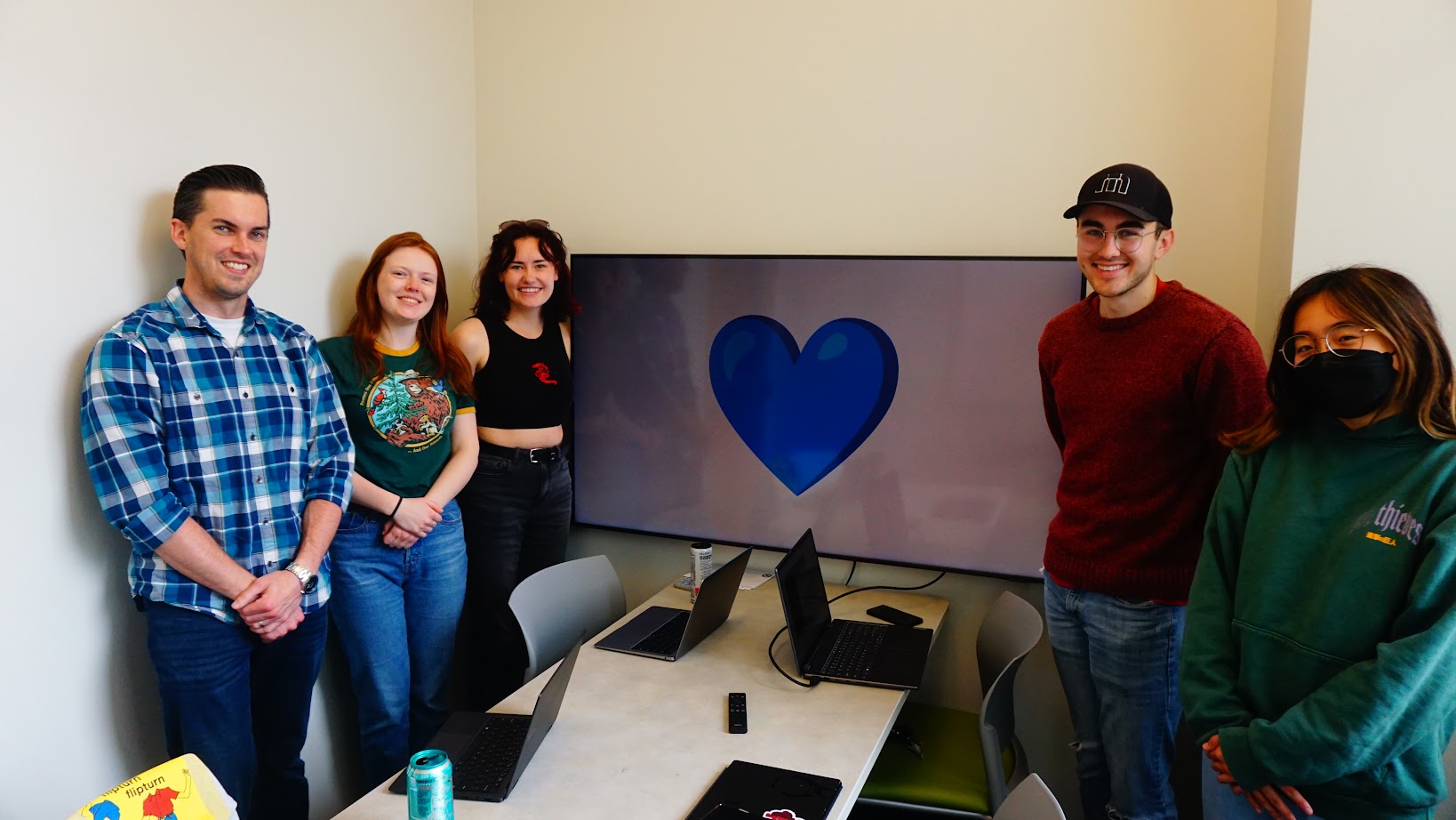Students and professor are with a computer that has a blue heart shown. The blue heart represents solidarity with human trafficking victims. 