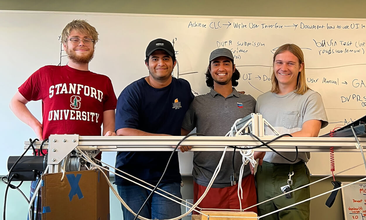 Four students stand next to treadmill for robot testing