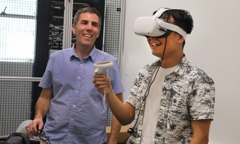 Professor guides a student as they use a VR headset