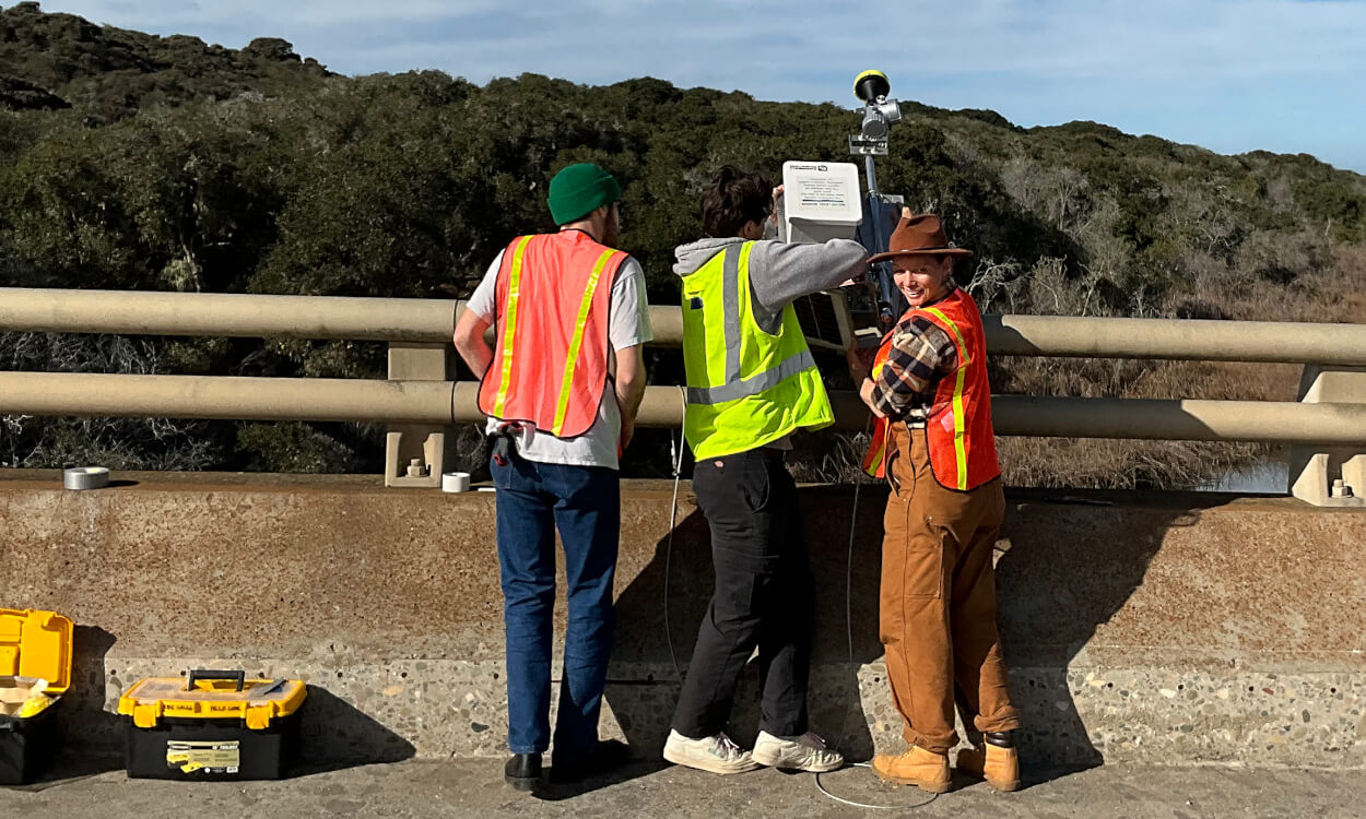 A group of engineering students, with the help of research fellow Serena Lee, shown in center, install a tide gauge on the Los Osos Creek Bridge